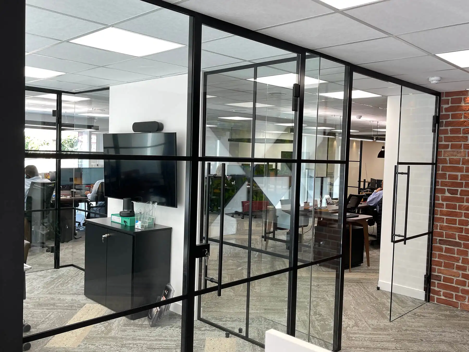 Black framed glass partitions in office with designer furniture