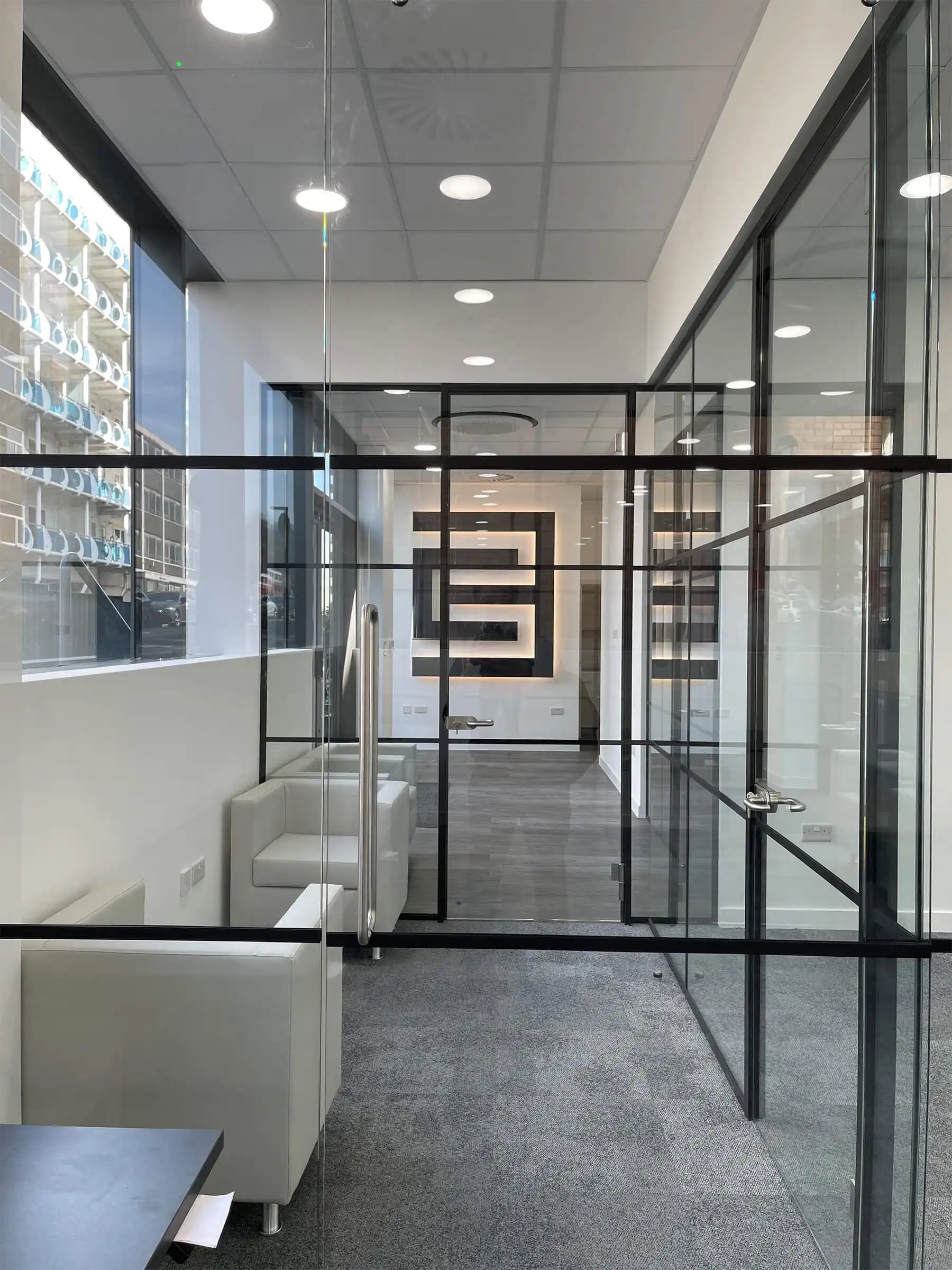 Black framed glass partitions in office with designer walls and floor