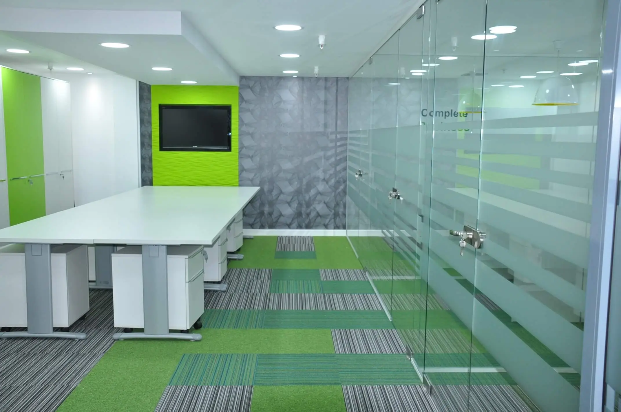 Designer flooring glass partitioning in office with desk pedestals and TV