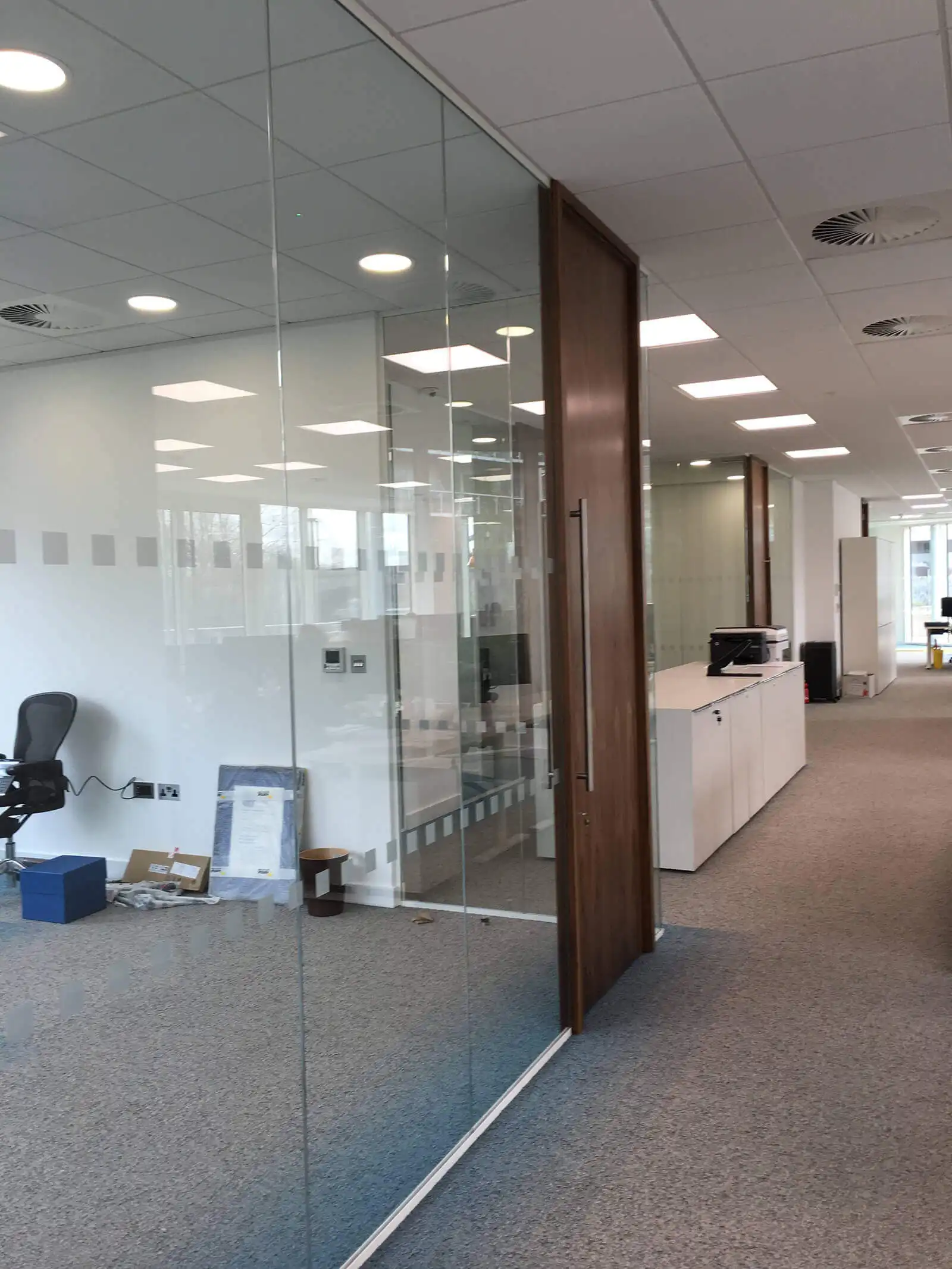 Glass partition with solid wood door with full height handle in office