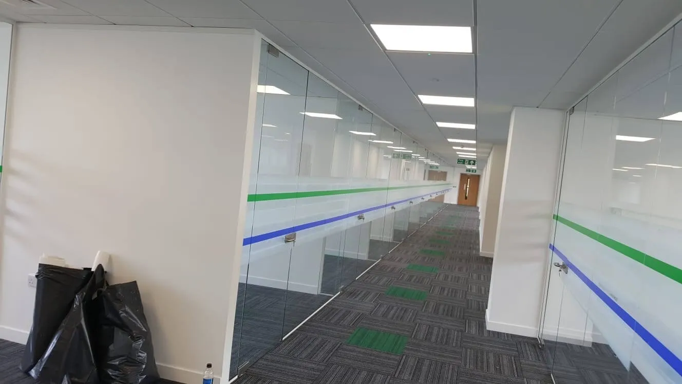 Large office area with frameless glass partitions and some charts in corner