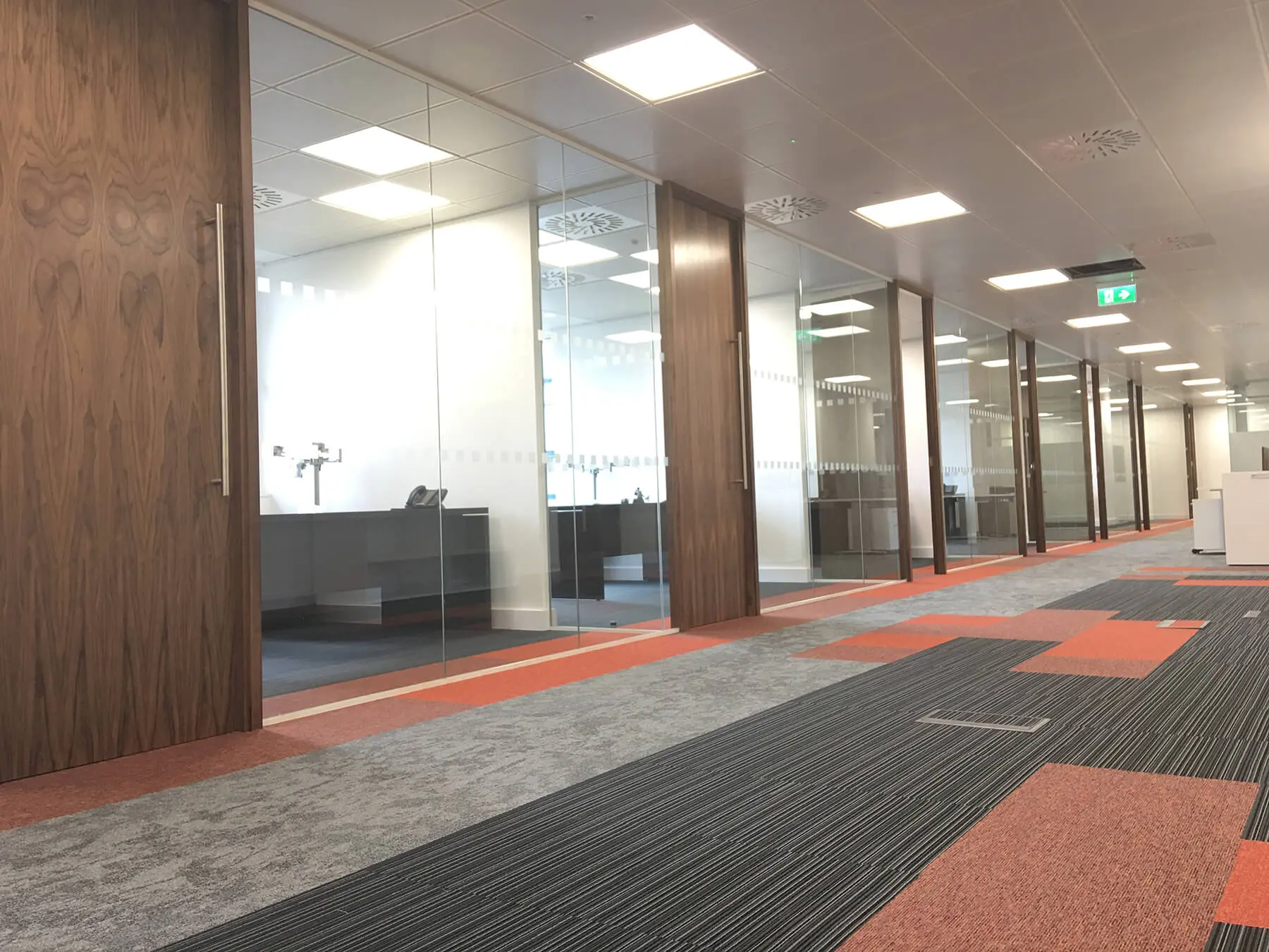 Large office space divided with glass walls with wood doors