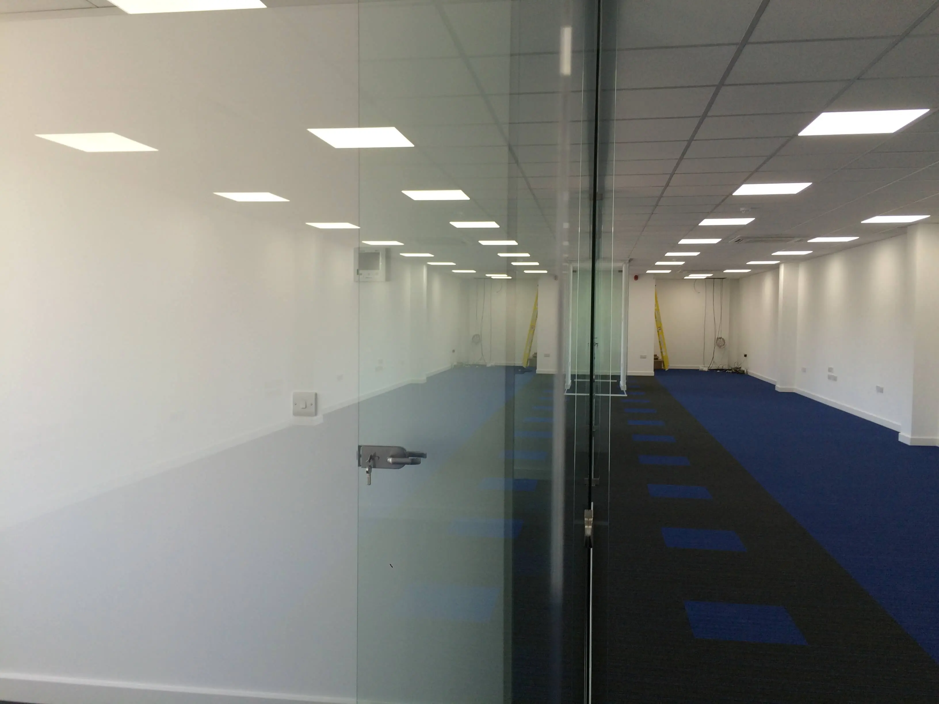Large office space with single glazed glass partitions and lighting