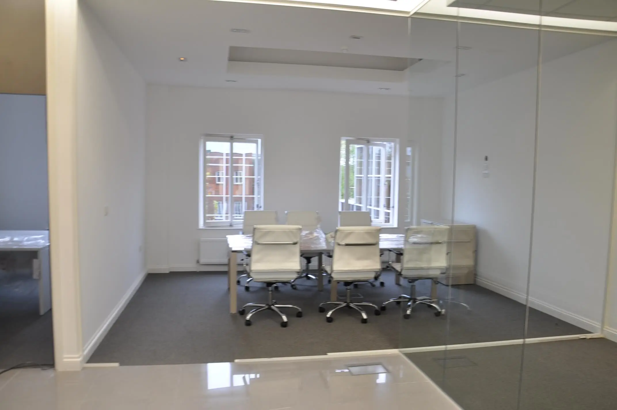 Meeting area with table white chairs and frameless glass partitions