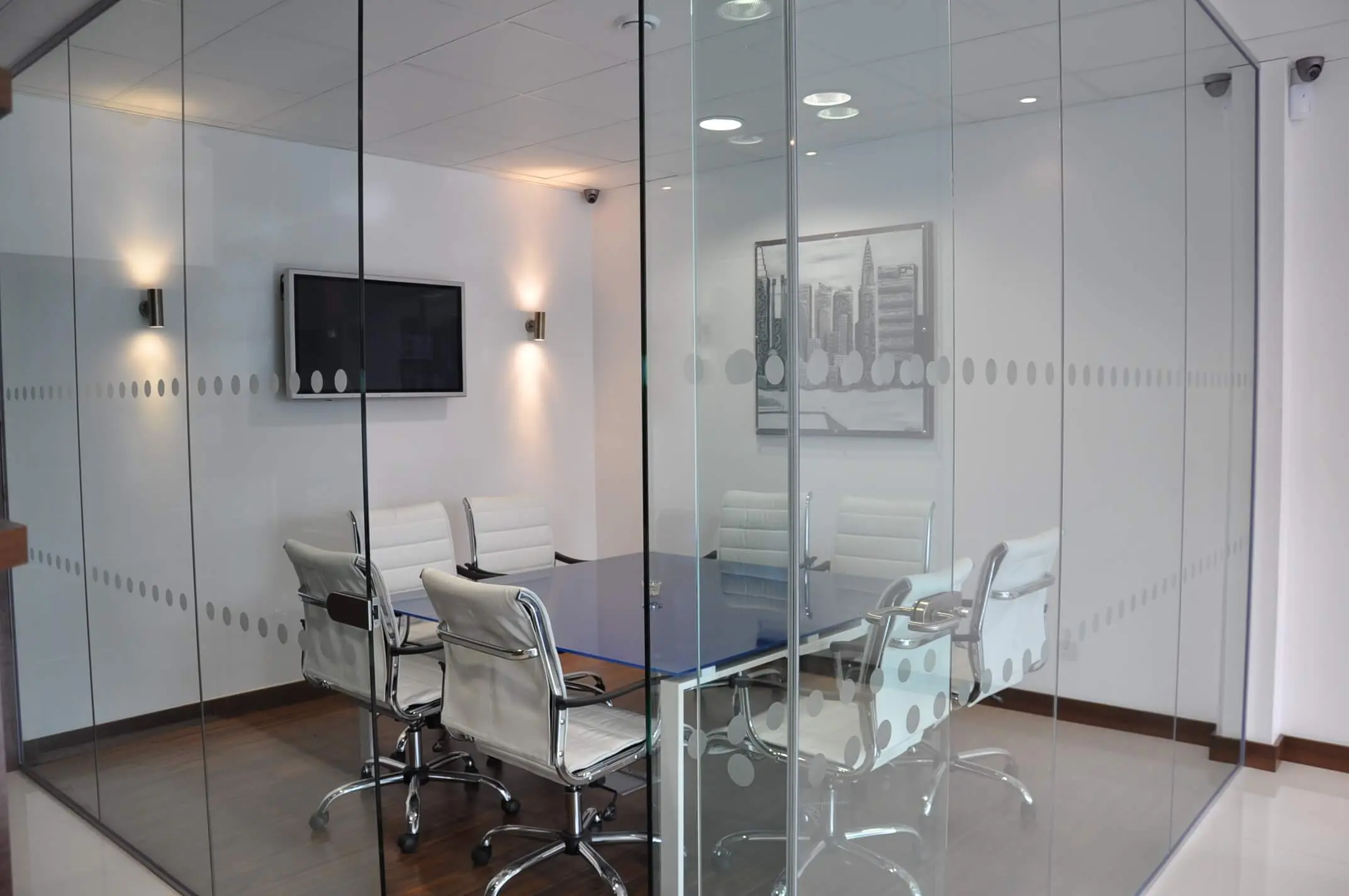 Meeting space with table and chairs around it in dotted glass office partitions