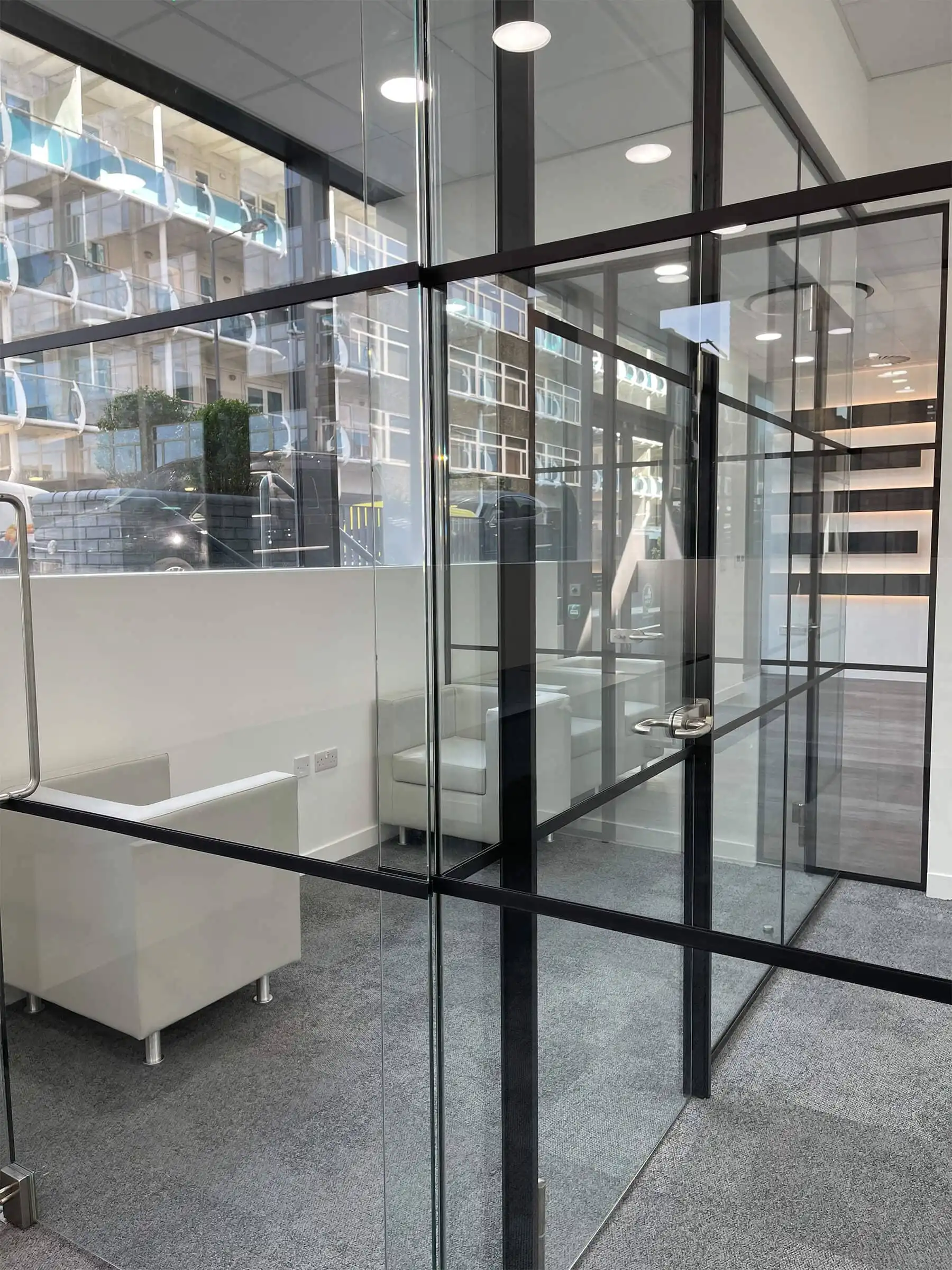 Office space with armchairs and divided with glass walls partitions