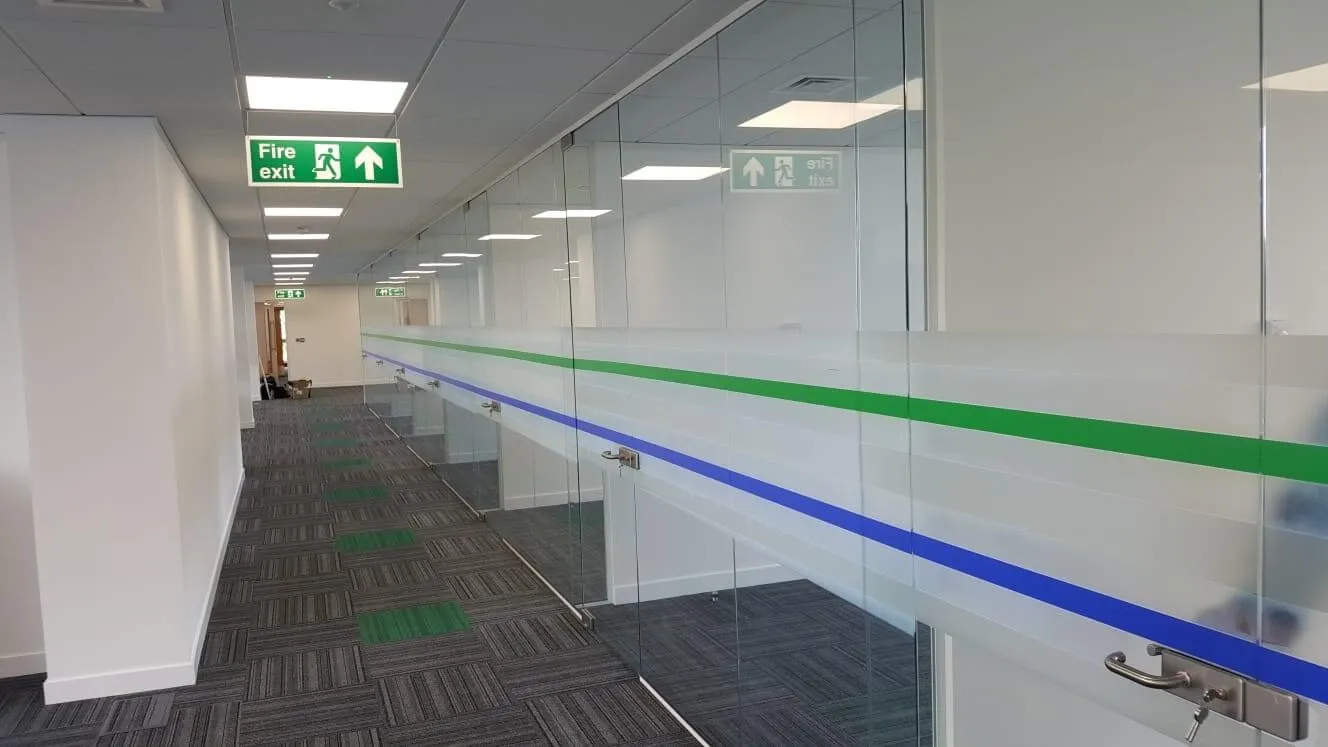 Office space with frameless glass partitions and fire exit sign board