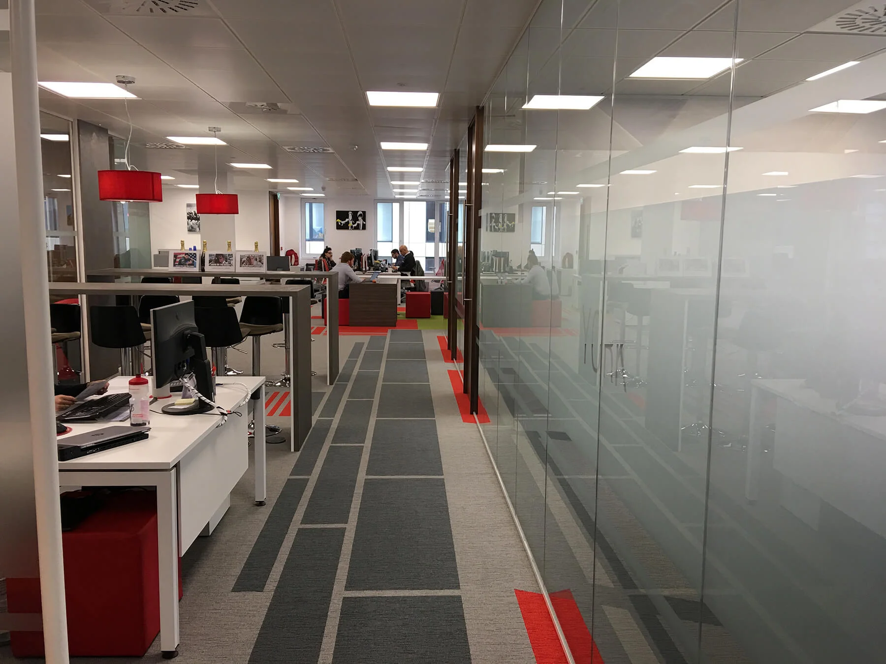Office space with high desks chairs designer floor and frameless glass partitions