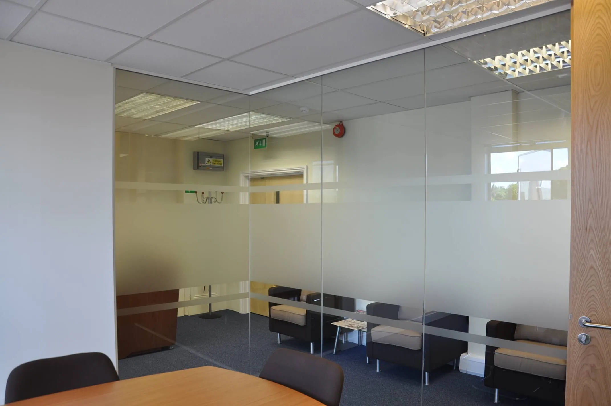 Office waiting space and meeting space divided with glass partitions
