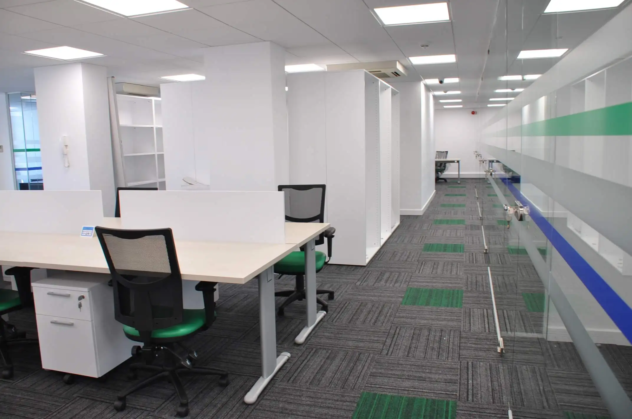 Office with back to back desks chairs pedestals and glass partition