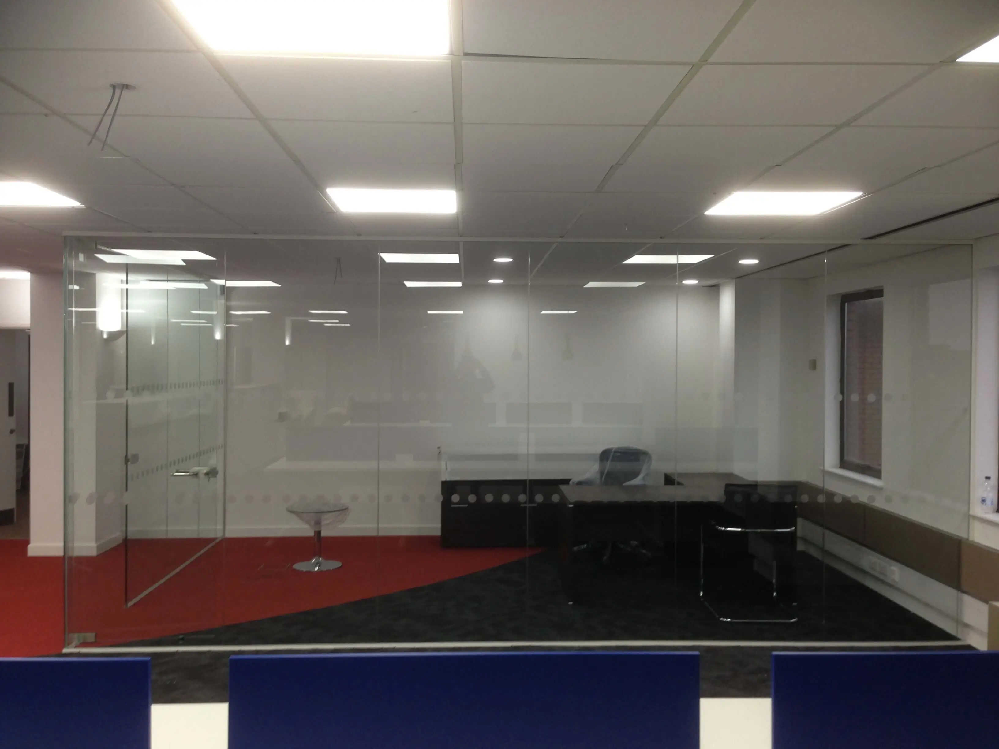 Private work space with executive desk chair and visitor chairs surrounded with frameless glass walls