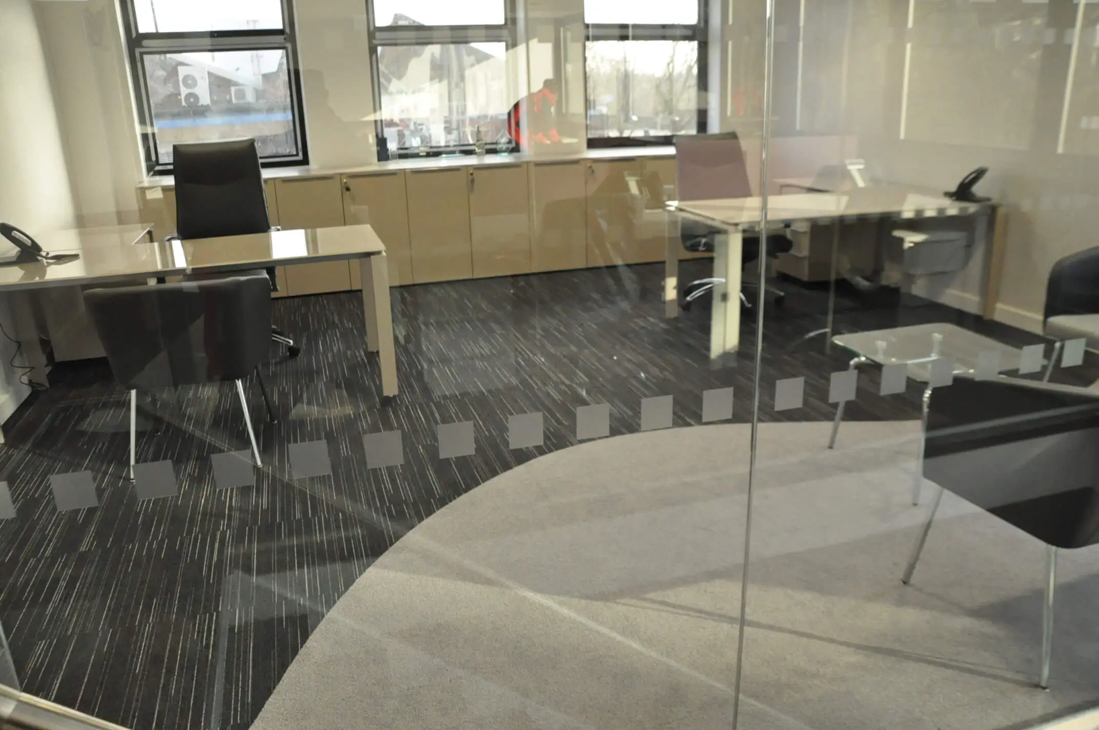 Private space with dotted glass manifestation and office desks and chairs