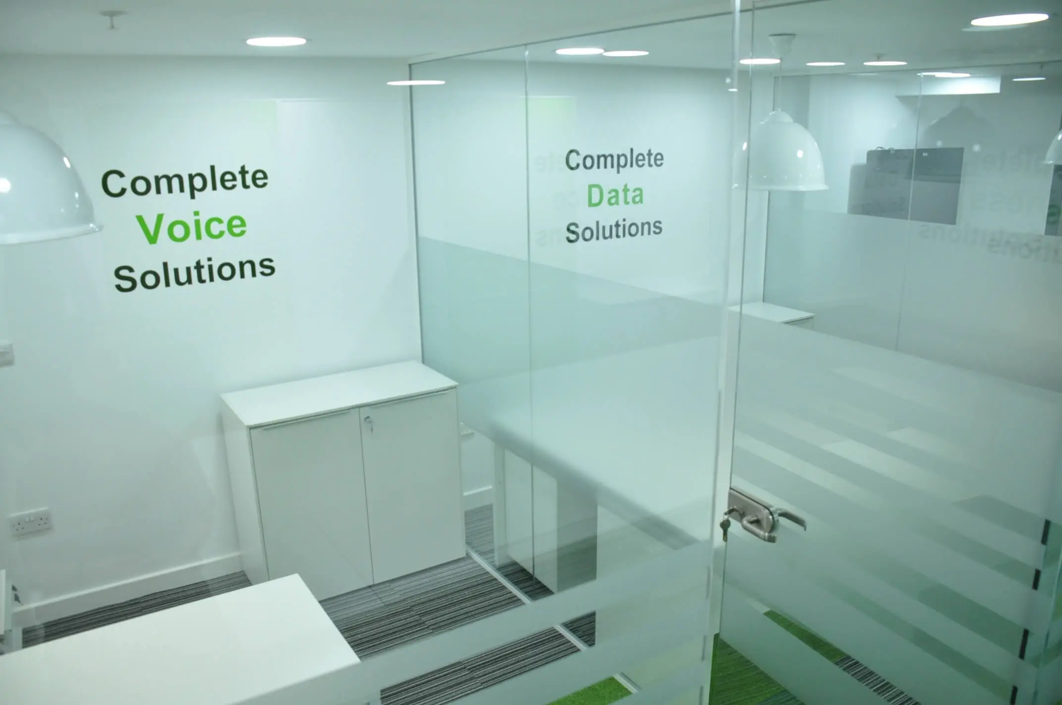 Small office space with glass partition and storage unit in it