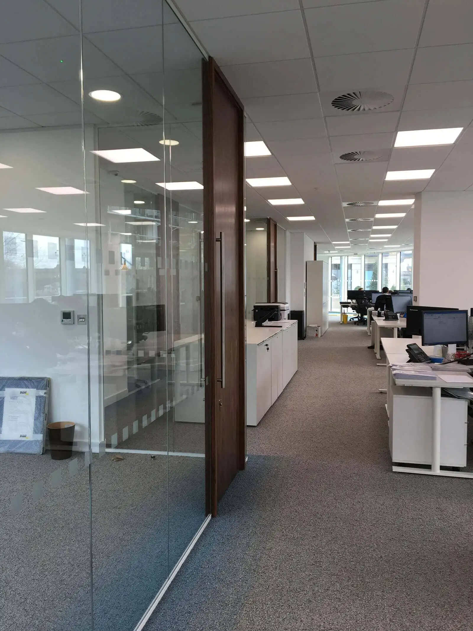 Workspace in office seperated with glass partition with solid wood doors